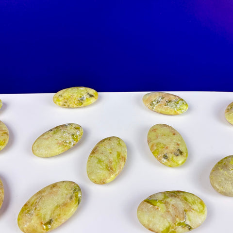 Polished Toxic Waste serpentine and mica palm stones with mottled lime green and tan patterns on a white surface.
