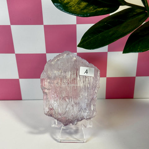 Vibrant pink Kunzite crystal variant A, with natural striations, displayed on a clear stand.