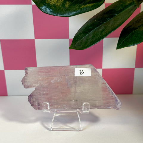 Vibrant pink Kunzite crystal slab, variant B, on a clear stand with a checkered background.