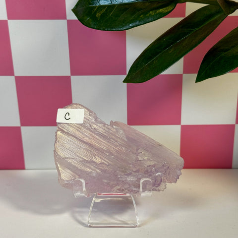 Vibrant pink Kunzite crystal variant C, with natural striations, displayed on a clear stand.