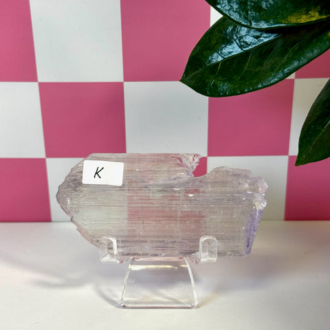 Vibrant pink Kunzite crystal slab with natural striations on a clear stand.
