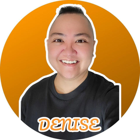 Smiling person with a shaved head and dark hair on top, wearing a black shirt with "DENISE" in orange.