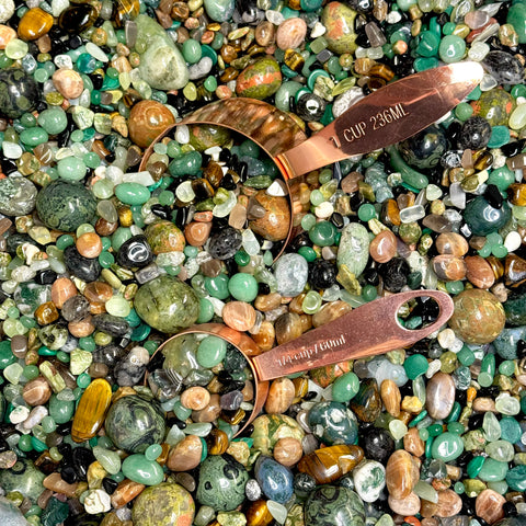 Witch’s Brew confetti mix of polished green, brown, and black gemstones in copper measuring cups.