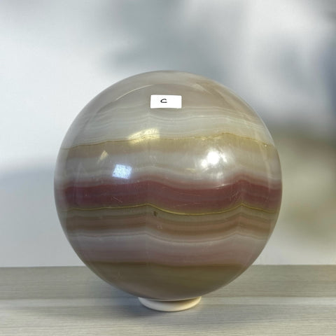XL Pink Banded Onyx Sphere, a polished crystal ball with natural pink, white, and brown bands.