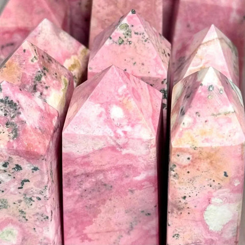 Pink rhodonite crystal towers with black and white inclusions.