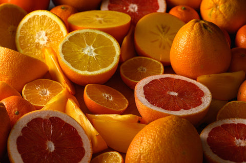 Vibrant citrus fruits: oranges, grapefruits, and tangerines, whole and sliced, in warm orange and red hues.