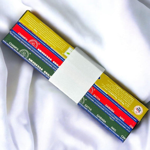 Assorted incense stick boxes in vibrant colors, including red, green, and yellow, on a white fabric background.