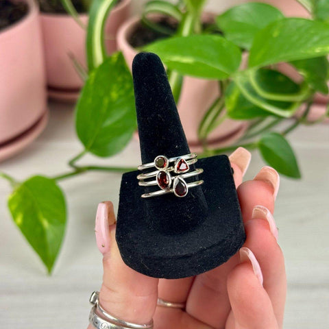 Sterling silver rings with red and green garnet gemstones on a black velvet display.