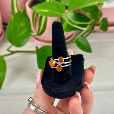 Sterling silver rings with vibrant orange carnelian stones on a black velvet display, July collection.