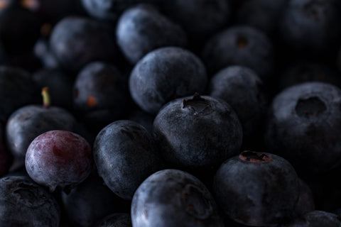 Close-up of fresh, dark blueberries with one reddish berry, evoking a "Lavender Dusk" mood.