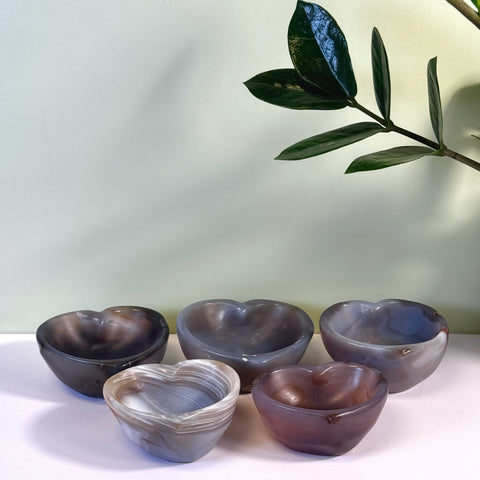 Polished agate heart bowls in varying shades of gray, white, and purple, with natural banding.