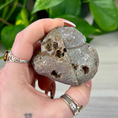 Rough grey agate geode pair with natural cavities, held in a hand.
