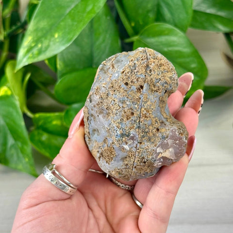 Rough grey and brown agate pair held in a hand, showing natural texture.