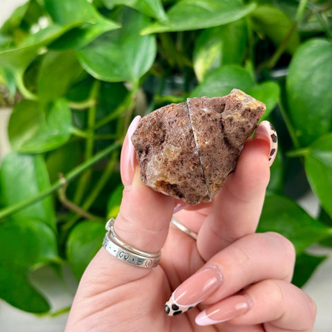 Rough brown agate pair held by fingers with pink and black leopard print nails.