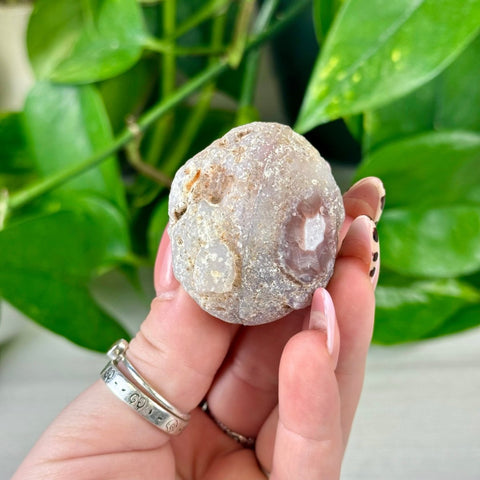 Rough, natural agate geode with white and purple hues held in a hand.