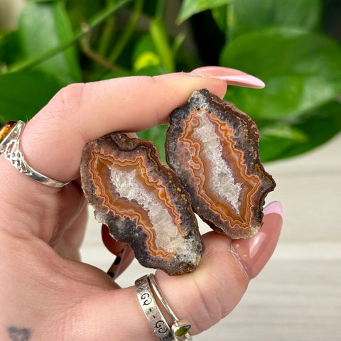 Agate Pairs (Y4) with natural brown, orange, and white bands, held in a hand.