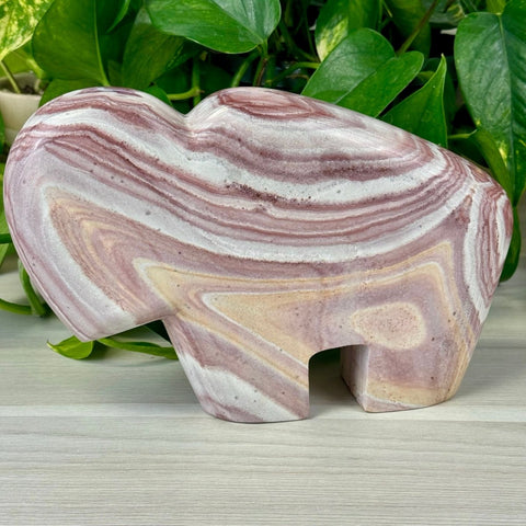 Billie The Bison, a carved Rainbow Rhyolite crystal in swirling pink, white, and beige.
