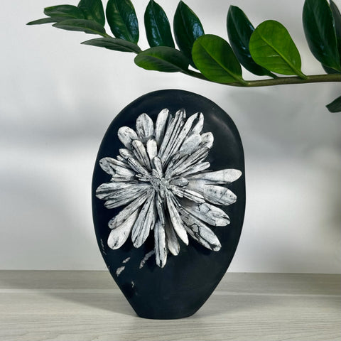 Black chrysanthemum stone free form with white flower carving, displayed on a light surface.