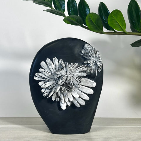 Black chrysanthemum stone free form with white floral patterns, on a light wood surface.