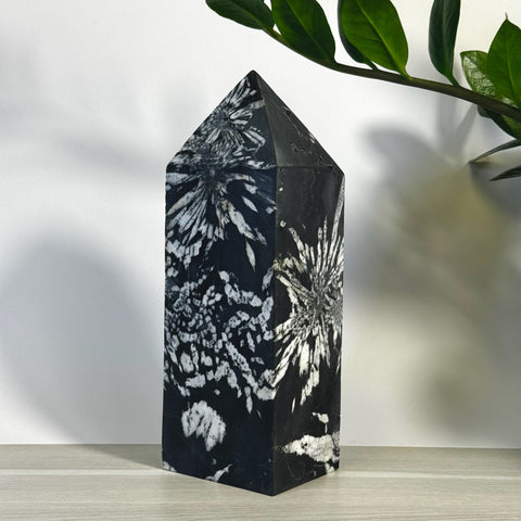 Black chrysanthemum stone tower with white floral patterns, pointed top, and polished finish.