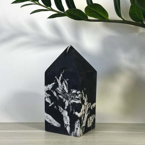 Black chrysanthemum stone tower with white floral patterns, pointed top.