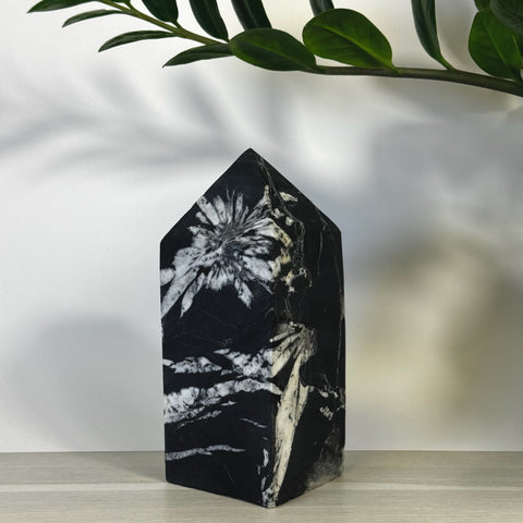 Black Chrysanthemum Stone Tower with white floral patterns, pointed top.