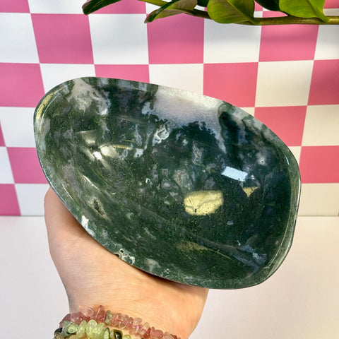 Curvy, polished moss agate bowl with deep green and white swirling patterns, held in a hand.