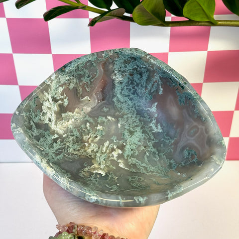 Curvy moss agate bowl with natural green and white patterns, held in a hand.
