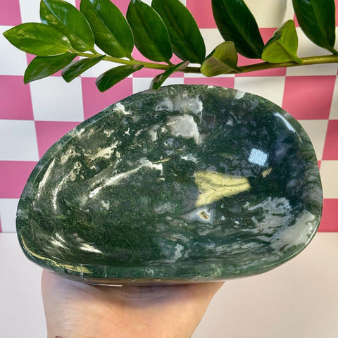 Curvy, polished moss agate bowl with deep green and white swirling patterns, held in a hand.
