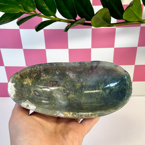 Curvy moss agate bowl with natural green, brown, and white patterns, held in a hand.