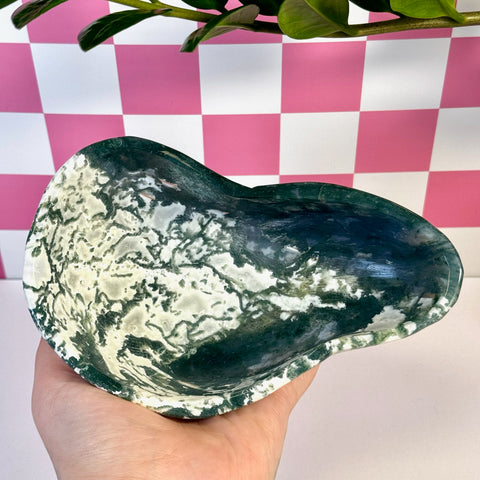 Curvy moss agate bowl with deep green and white swirling patterns, held in a hand.