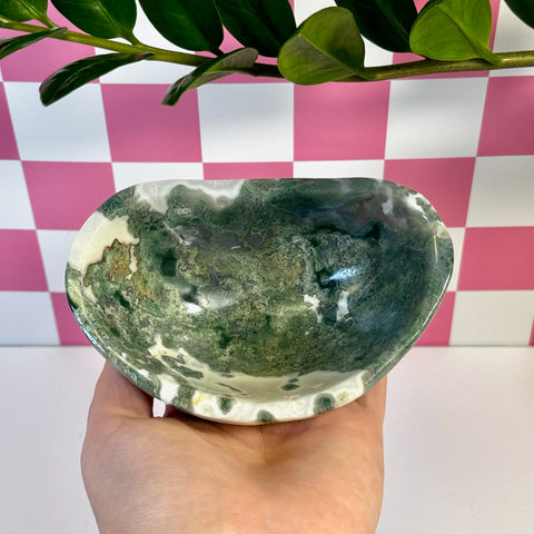 Curvy moss agate bowl with deep green and white patterns, held in a hand.