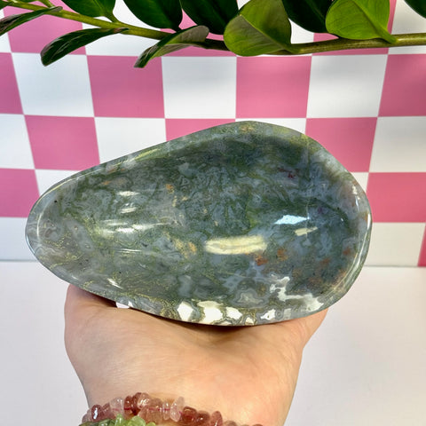 Curvy moss agate bowl with natural green, white, and brown patterns, held in a hand.