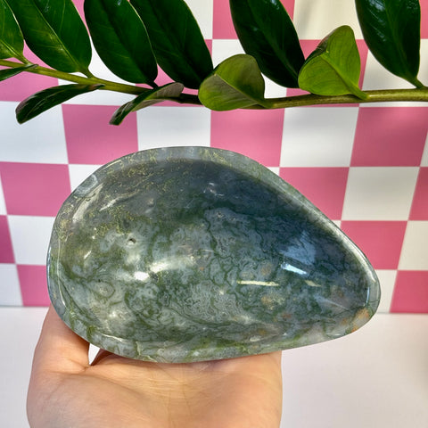 Curvy moss agate bowl with natural green and white patterns, held in a hand.