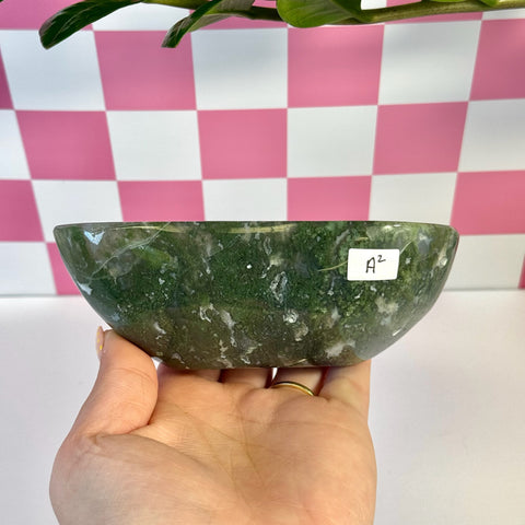 Curvy moss agate bowl, deep green with white inclusions, held in hand.