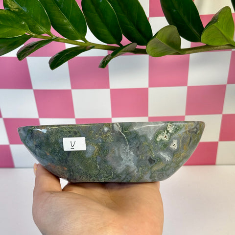 Curvy moss agate bowl with green, white, and brown swirling patterns, held in a hand.