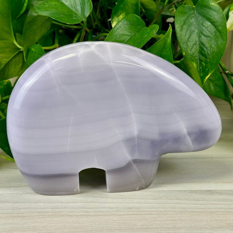 Lavender fluorite bear carving with smooth, polished surface and subtle banding.