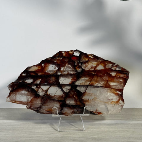 Fire Quartz slice with deep reddish-brown and clear crystalline sections on a stand.
