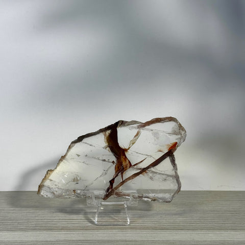 Clear Fire Quartz slice with reddish-brown inclusions on a stand.