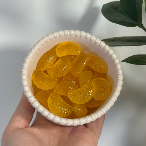 Vibrant orange fluorite clementine slices in a white scalloped bowl, held in a hand.