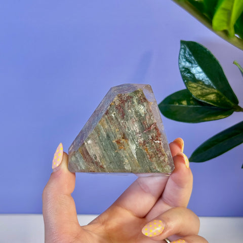 Garden Quartz Free Form, clear with green and reddish-brown inclusions, held by a hand with yellow polka dot nails.