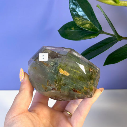 Faceted garden quartz free form with green and brown inclusions, held in a hand.