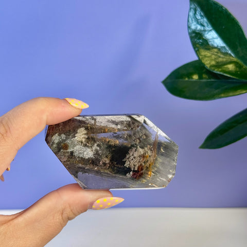 Garden Quartz Free Form with dark green, brown, and white inclusions, held by a hand with yellow polka dot nails.