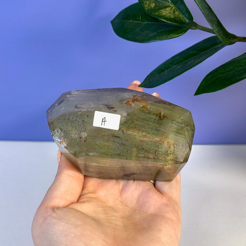 Hand holding a large, faceted Garden Quartz Free Form crystal with green inclusions.