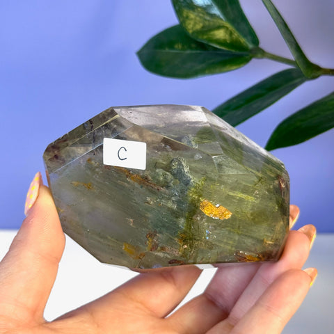 Garden Quartz Free Form, variant C, with green, brown, and yellow inclusions, held in a hand.