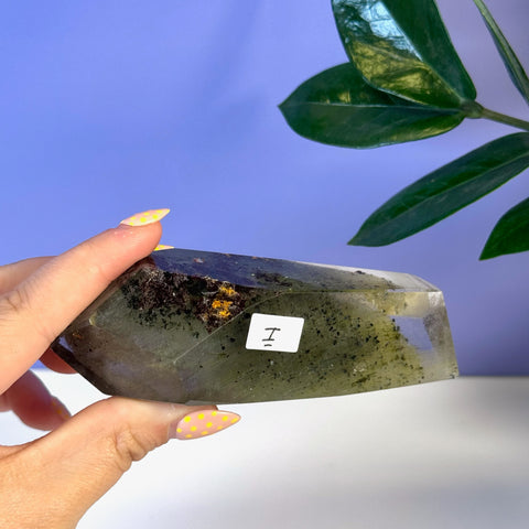 Garden Quartz free form crystal, clear with dark green and yellow inclusions, held by hand.