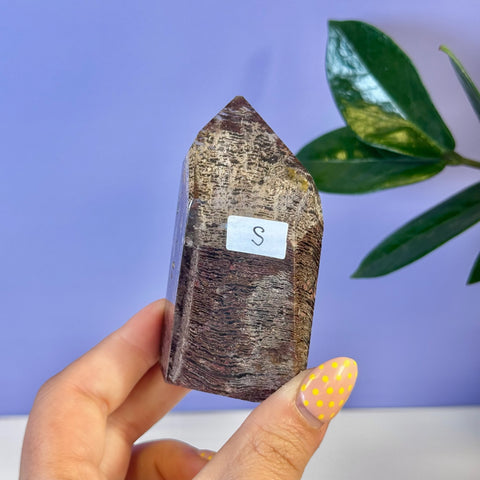 Small, dark brown Garden Quartz free form crystal with a pointed top, held in hand.