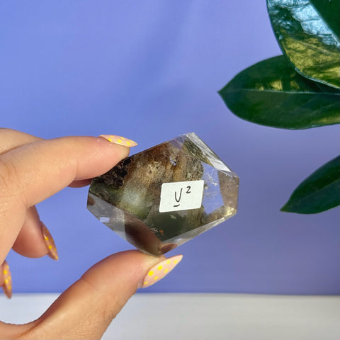 Garden Quartz Free Form, V2, held in hand, showing clear crystal with green and brown inclusions.