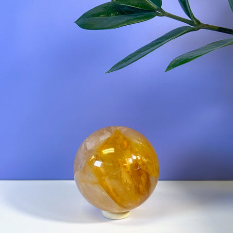 Girasol Golden Healer Sphere, a polished, translucent yellow-orange crystal ball on a white stand.