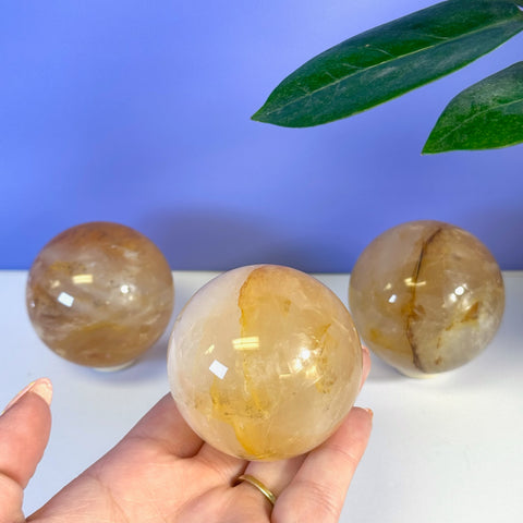 Three Girasol Golden Healer spheres, one held in a hand, showcasing warm yellow and orange tones.